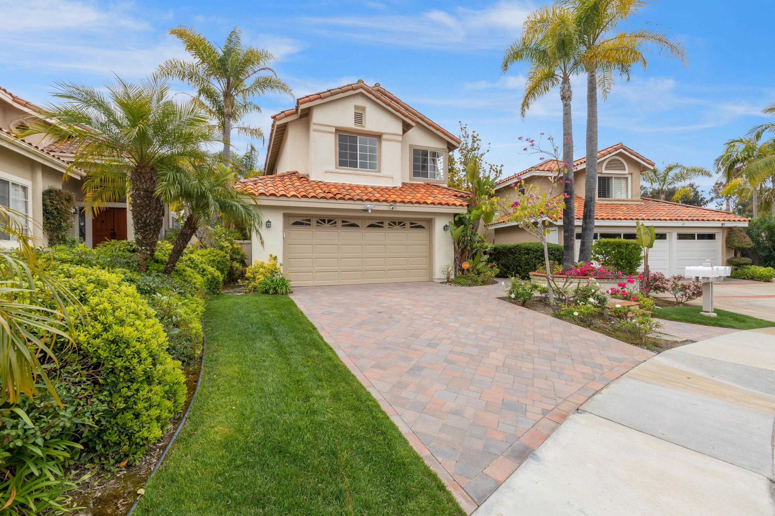 Two-story residence with tile roof and brick paver driveway