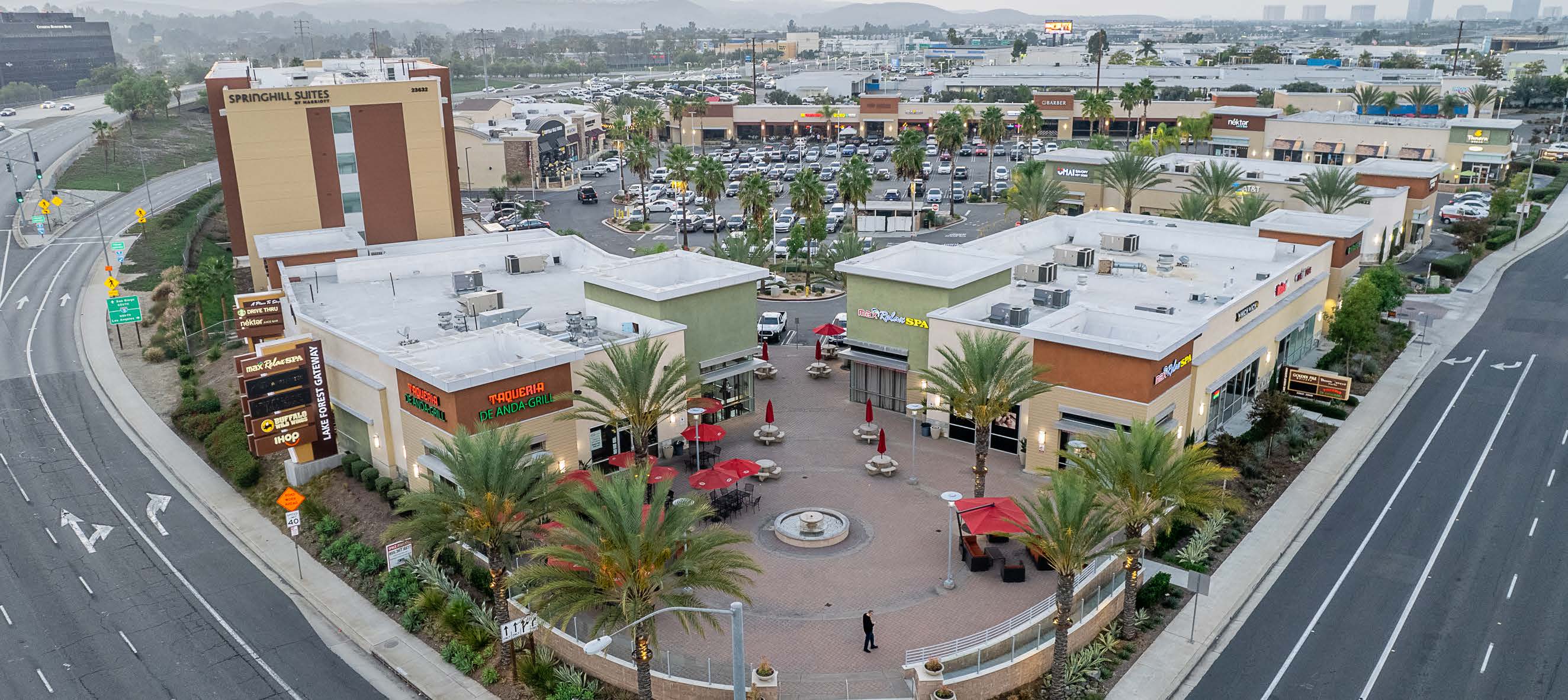 Lake Forest Gateway plaza with fountain and storefronts at dusk