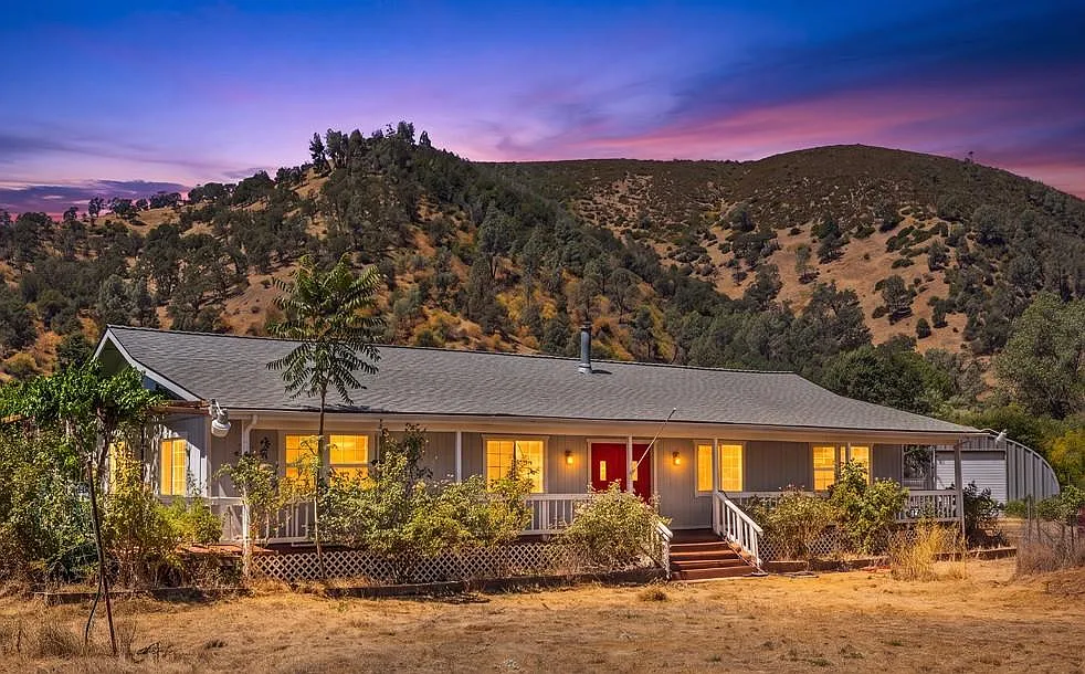 Single-story home at 1633 New Long Valley Rd in Clearlake Oaks at dusk with rolling hills behind
